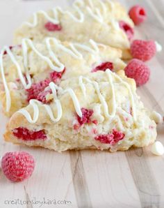 two raspberry scones with white frosting and some raspberries on the side