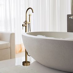 a large white bath tub sitting next to a couch in a living room under a window