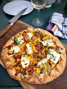 a pizza sitting on top of a wooden cutting board next to a glass of wine