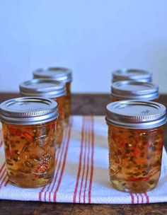 four mason jars filled with liquid sitting on top of a table next to a red and white towel