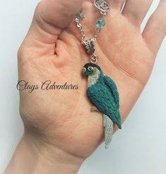 a hand holding a small green bird charm on it's wrist with charms attached to it