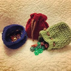 three crocheted bags with dices in them sitting on a white surface next to each other