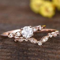 a close up of a diamond ring on a piece of wood with flowers in the background