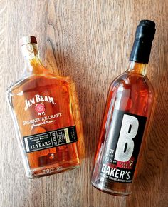 two bottles of booze sitting on top of a wooden table next to each other