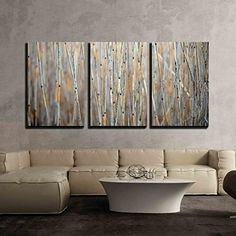 three paintings are hanging on the wall in a living room, one is white and the other is brown