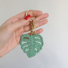 a hand holding a green crocheted key chain