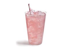 a pink drink with ice and straw in a tall glass on a white table top