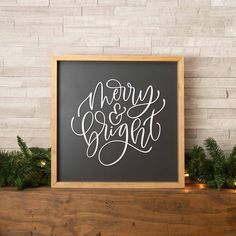 a chalkboard with the words merry and bright written on it in front of some evergreen branches