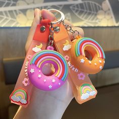 a person holding three different colored donuts keychains in their hand with rainbows and stars on them