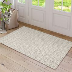 a large white rug on the floor in front of a door with two planters