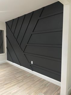 an empty room with wood flooring and black painted wall art work on the walls