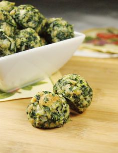 a bowl filled with broccoli balls sitting on top of a wooden cutting board