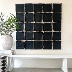 a white bench sitting in front of a black and white wall hanging on it's side