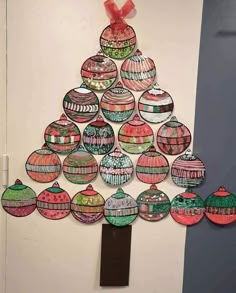 a christmas tree made out of ornaments hanging on the wall in front of a door