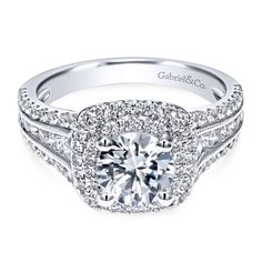 a white gold engagement ring with an intricate halo setting and round diamonds on the band