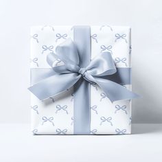 a wrapped gift box with a blue ribbon and bow on it's side, against a white background