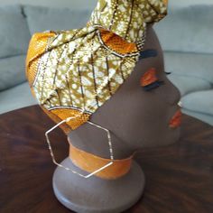 the head of a mannequin wearing an orange and yellow scarf on it's head