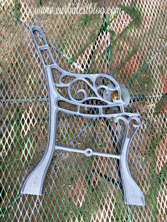 a metal bench sitting on top of a green grass covered park area next to a fence