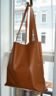 a brown leather bag hanging on a window sill