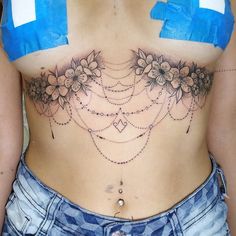 a woman's stomach with flowers and chains attached to the bottom of her belly