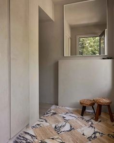 an empty room with a bench and stool on the floor in front of a window