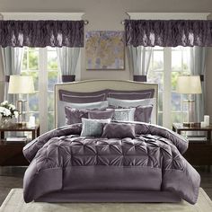 a bed in a bedroom with purple comforter and pillows