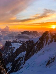 the sun is setting over some mountains with snow on them and clouds in the sky