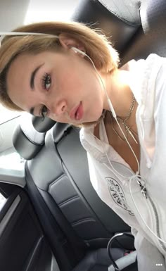 a woman sitting in the back seat of a car wearing headphones