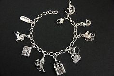 "A collection of silver plated fairy tale themed charms have been dispersed around a shimmering silver plated bracelet chain in this handmade charm bracelet. This fantasy storybook charm bracelet is then completed with a lobster clasp and a 1/2 inch of chain at the end for adjustable sizing. Charms in this bracelet include a \"Believe\" tab charm, pegasus charm, storybook charm, dragon charm, castle charm, princess charm with crown charm, unicorn charm, mermaid charm, and a fairy on the moon cha Whimsical Silver Charms For Gifts, Whimsical Silver Dangling Charms, Themed Sterling Silver Charms, Themed Silver Sterling Charms, Adjustable Silver Fantasy Bracelet, Themed Silver Jewelry With Charms, Whimsical Silver Charm Bracelet, Whimsical Silver Bracelet Jewelry, Whimsical Nickel-free Silver Charm Bracelet