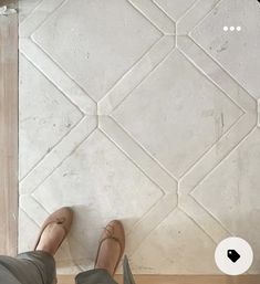 a person standing in front of a tile wall with their feet up on the floor