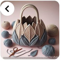 a knitted bag sitting on top of a table next to balls of yarn and crochet hooks