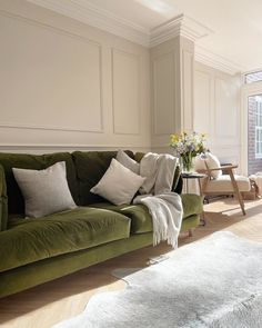 a living room with green couches and white walls