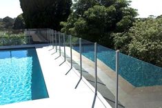 a pool fence is next to an empty swimming pool with trees in the back ground