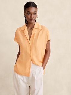 We cut this modern resort shirt with easy dolman sleeves and a relaxed fit.  For fabric, we selected our signature silk charmeuse—a favorite for its beautiful drape, satin-like shine, and ease of care.  Relaxed fit.  Resort collar.  Dropped shoulder.  Troca shell button front.  Straight hem.  Unlined.  Relaxed fit.  Short sleeves.  Hip length.  Model: Size S, 5'10" (178cm). Elegant Silk Short Sleeve Shirt, Black Silk Short Sleeve Blouse, Luxury Short Sleeve Silk Shirt, Luxury Black Short Sleeve Camp Shirt, Silk Button-up Blouse With Hidden Closure, Resort Shirt, Silk Camisole, Tailored Shirts, Silk Charmeuse