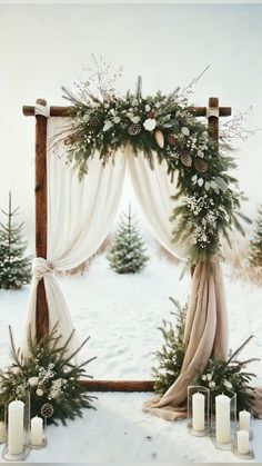 an outdoor winter wedding ceremony with white flowers, greenery and candles on the snow covered ground