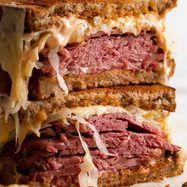 a roast beef sandwich cut in half with melted cheese on the top and meat below