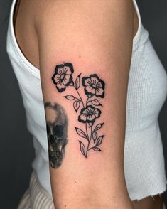 a woman with a skull and flowers tattoo on her arm