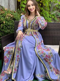 a woman is sitting on a bench wearing a blue dress with gold trimmings