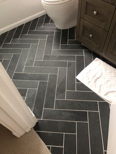 a white toilet sitting in a bathroom next to a black and white tile flooring