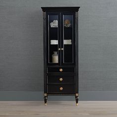 a tall black cabinet with glass doors and gold trimmings on the bottom shelf