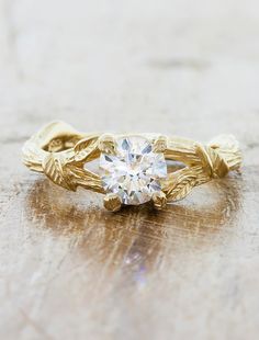 a close up of a ring with a diamond in it on a wooden table top