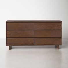 a wooden dresser with four drawers and two doors on one side, in front of a white wall