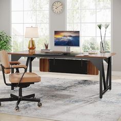 an office desk with a computer on it in front of a large window and clock