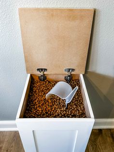 an open box filled with coffee beans on top of a hard wood floor next to a wall