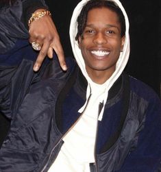 a man with dreadlocks and a hoodie smiles at the camera as he poses for a photo