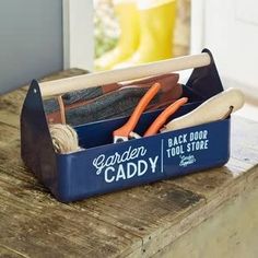 a blue caddy filled with gardening tools on top of a wooden table