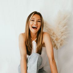 a woman sitting on the floor with her mouth open and eyes wide open, smiling