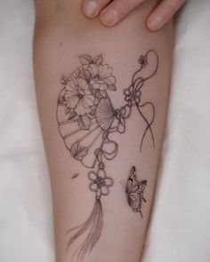 a woman's leg with flowers and a fan on it