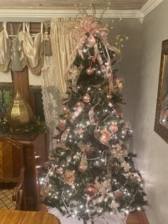 a decorated christmas tree in the corner of a room with gold and silver ornaments on it