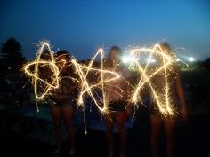 two girls holding sparklers spelling out the word love